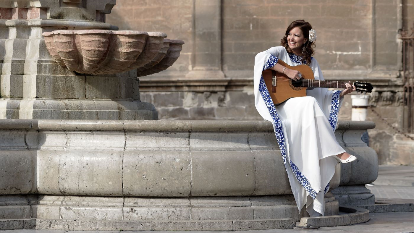 Farah Siraj plays guitar by a fountain