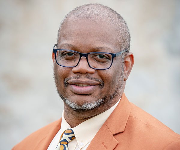 Reginald "Reggie" Thomas sits at a Steinway piano speaking into a microphone