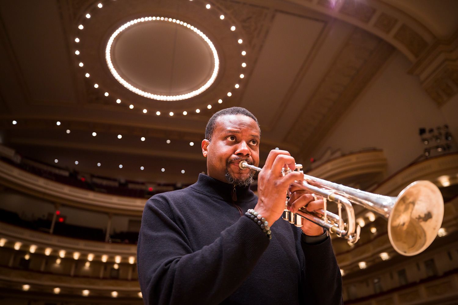 Sean Jones plays trumpet, the lights of Stern Auditorium above