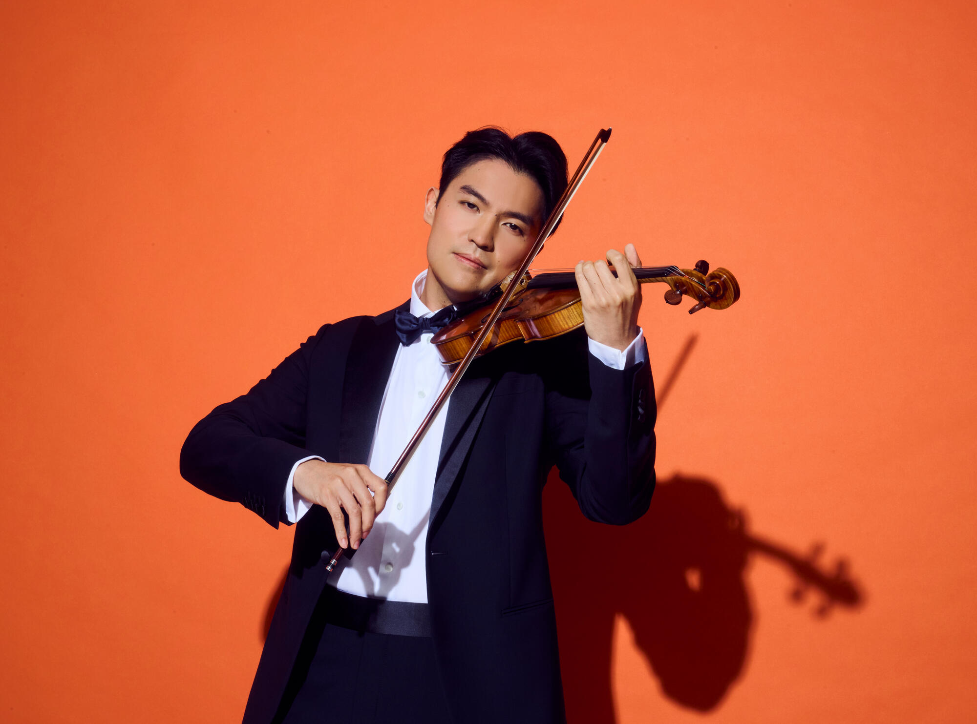 Ray Chen plays violin wearing a suit and bowtie